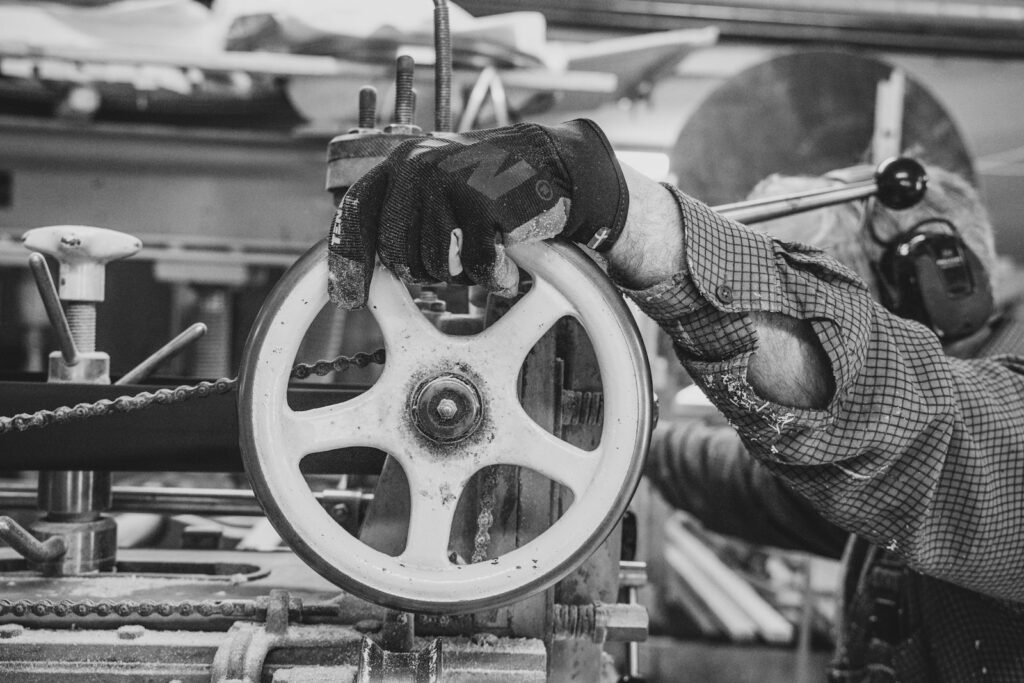 Main gantée d’un ouvrier actionnant une roue de machine dans un atelier